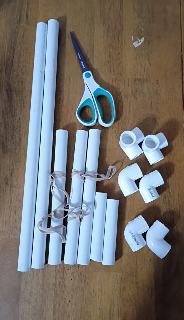 The pieces of the loom: two long lengths of pvc (approx 2 ft long), three medium lengths (approx 1 ft long) and 2 short lengths (approx half a foot long), as well as four elbows and two 3-way elbows.